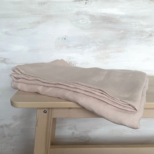 Prześcieradło lniane bez gumki płaskie beżowo różowe leży na drewnianym stoliku