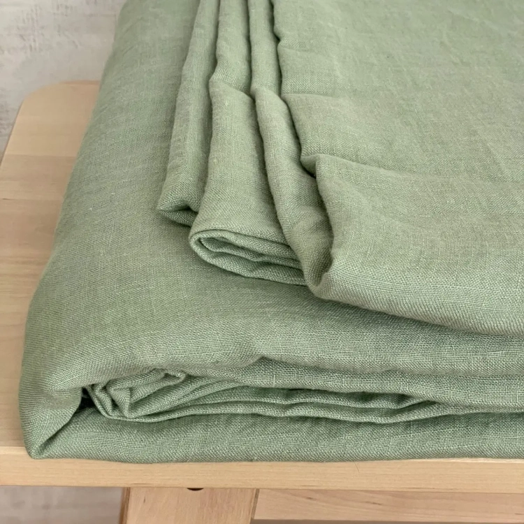 złożone jasnozielone prześcieradło z lnu, leży na drewnianej ławie