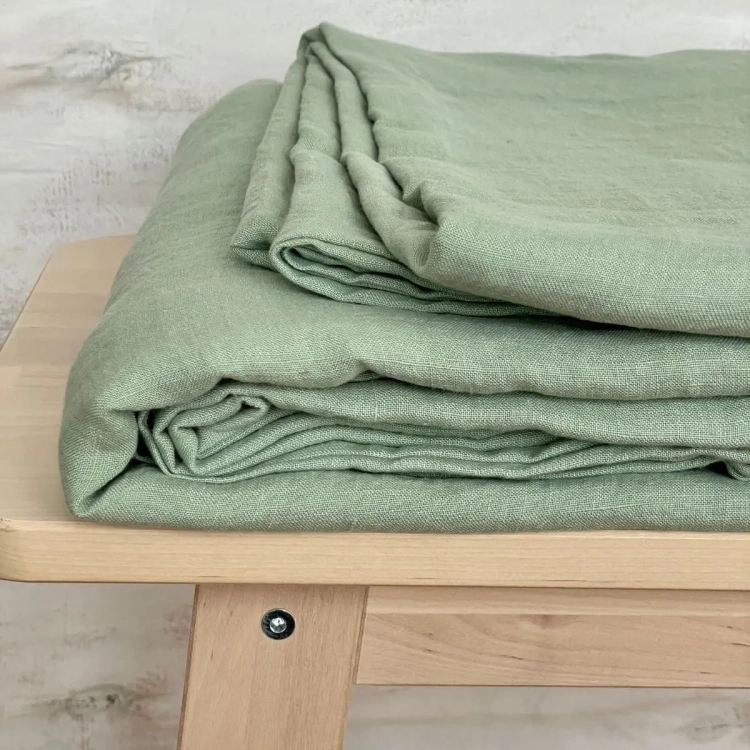 Lniane prześcieradło jasnozielone leżące na jasnej drewnianej ławie