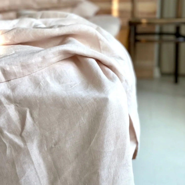poszwa na kołdrę lniana w kolorze beżowego różu leżąca na narożniku łóżka
