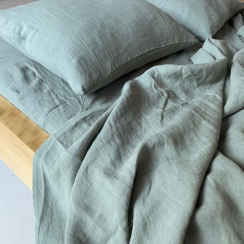 fragment zielonej eukaliptusowej lnianej pościeli na łóżku z zielonym prześcieradłem