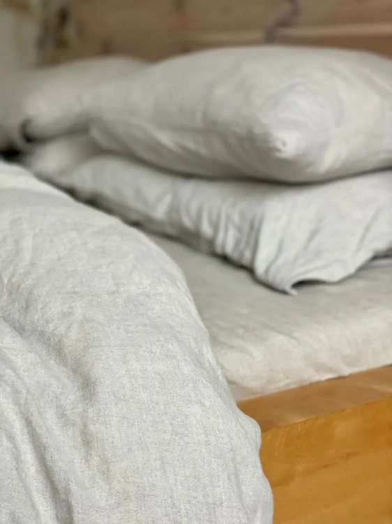 pościel lniana naturalna szarobeżowa  na drewnianym łóżku, poduszki, prześcieradło, fragment kołdry