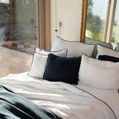 poduszki lniane białe i granatowe leżą na łóżku