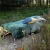 łózko ogrodowe z pościelą z motywem lasu i kolorowymi poduszkami, na tle lasu