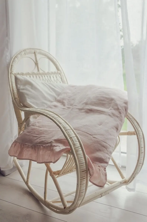 Różowe lniane poduszki z falbanami na bujanym fotelu. Styl romantyczny, prowansalski