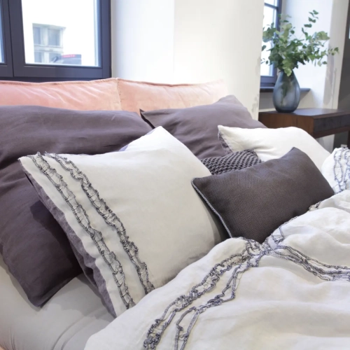 poduszki lniane granatowe i beżowe z falbanką na łóżku