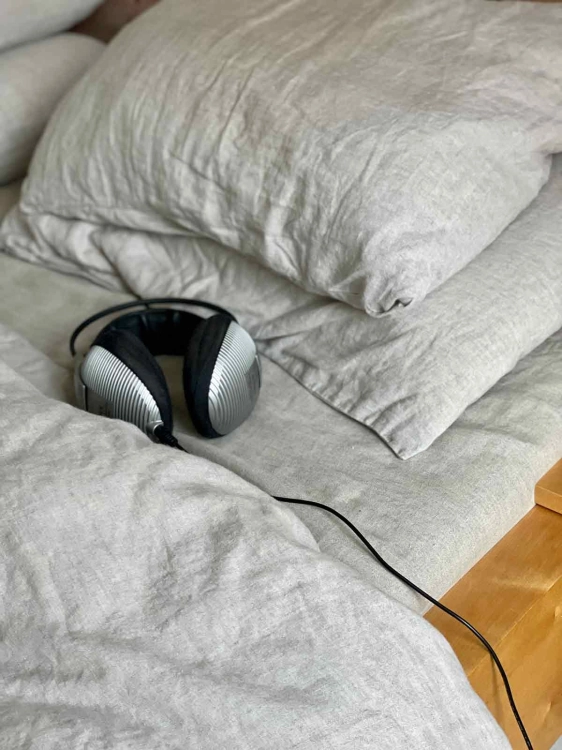 Lniane prześcieradło z gumką natural szaro beżowe
Słuchawki leżą w lnianej pościeli na drewnianym sosnowym łóżku