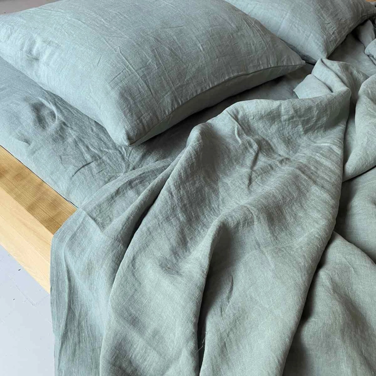 Prześcieradło z lnu zielone PURE eucalyptus green,
Fragment drewnianego łóżka z  zieloną eukaliptusową pościelą