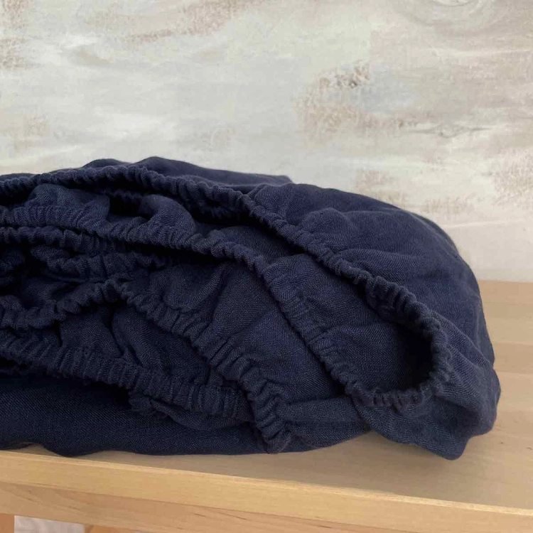 Lniane prześcieradło z gumką granatowe navy blue
Zwinięte granatowe prześcieradło z lnu na drewnianej ławie