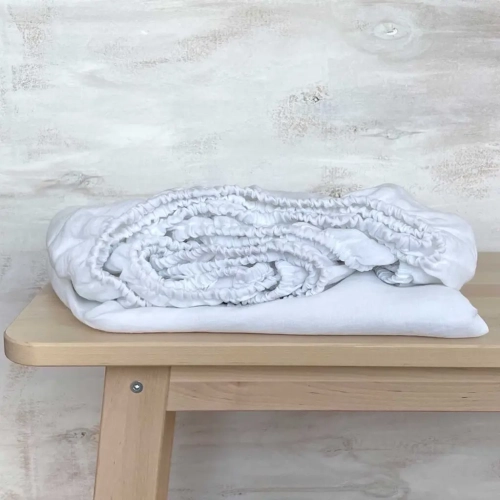 Białe lniane prześcieradło z gumką snow white
Śnieżnobiałe prześcieradło z lnu z gumką, zwinięte leży na drewnianym stole