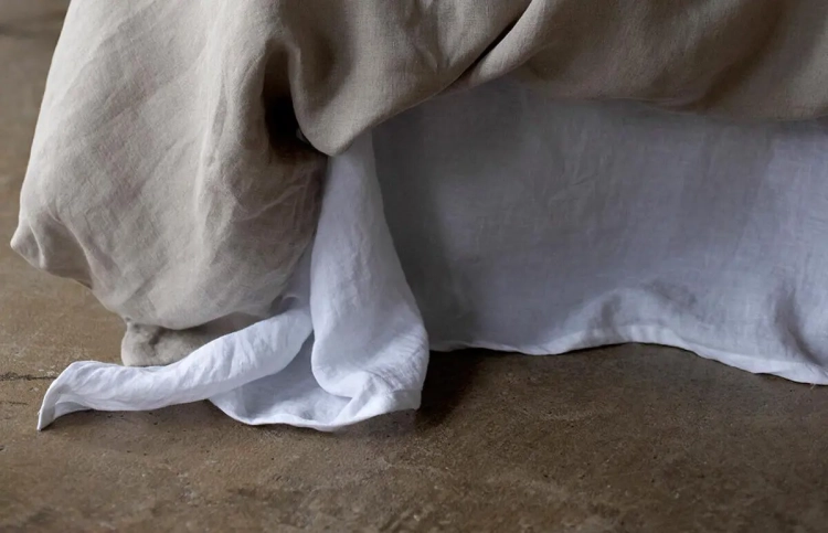 kołdra w lnianej naturalnej poszewce i białe lniane prześcieradło - fragment łóżka - detal