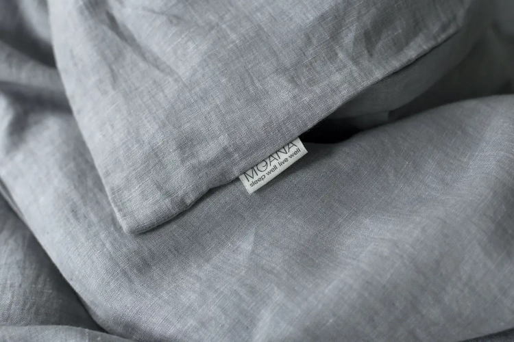poszewka lniana szara SILVER BIRCH. Detal, struktura melanżu, metka z logo marki MOANA