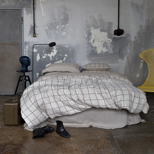 komplet pościeli lnianej GRID w kolorze naturalnym w czarną kratę leżą na łóżku z lnianą naturalną pościelą