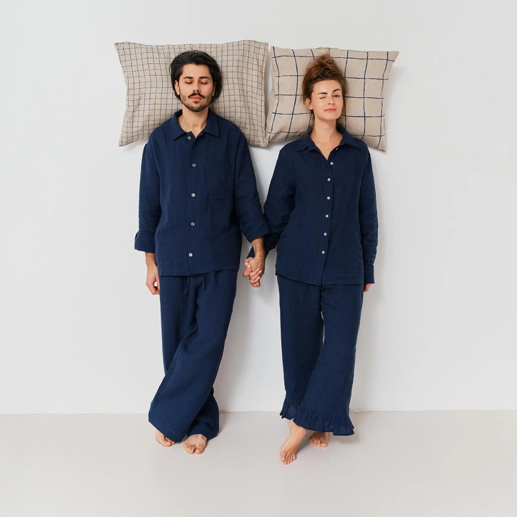 para w granatowych lnianych piżamach oparta o ścianę, za głowami poduszki w granatową kratę
