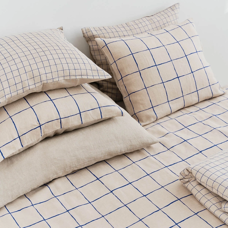 Zestaw poduszek lnianych GRID w granatową dużą i małą kratkę. Fragment łóżka