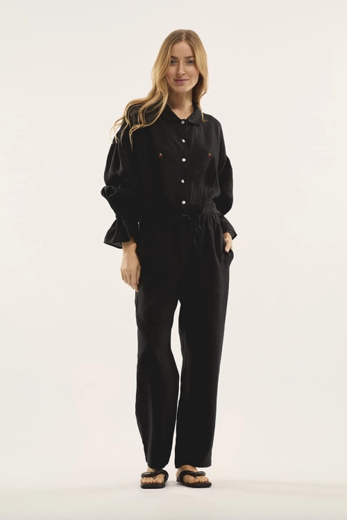 Modelka w czarnej lnianej piżamie. Koszula z długim rękawem, długie spodnie.