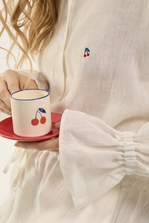 Motyw wisienek na białej lnianej koszuli i filiżance