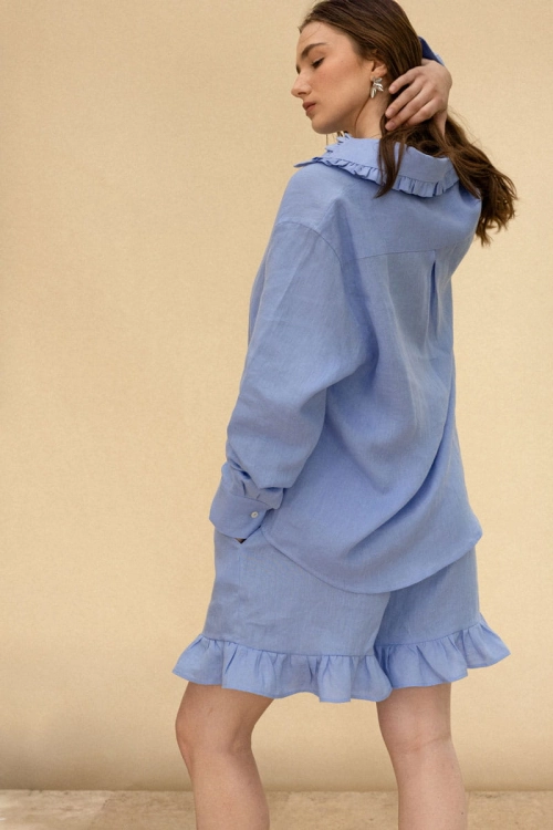 Tył koszuli z lnu – elegancka, przewiewna koszula w odcieniu błękitu, luźny krój. W zestawie z szortami z falbanką