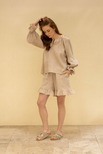Modelka w lnianej bluzce z rękawem z falbaną i krótkich spodenkach zakończonych falbanką - stylowy zestaw na lato