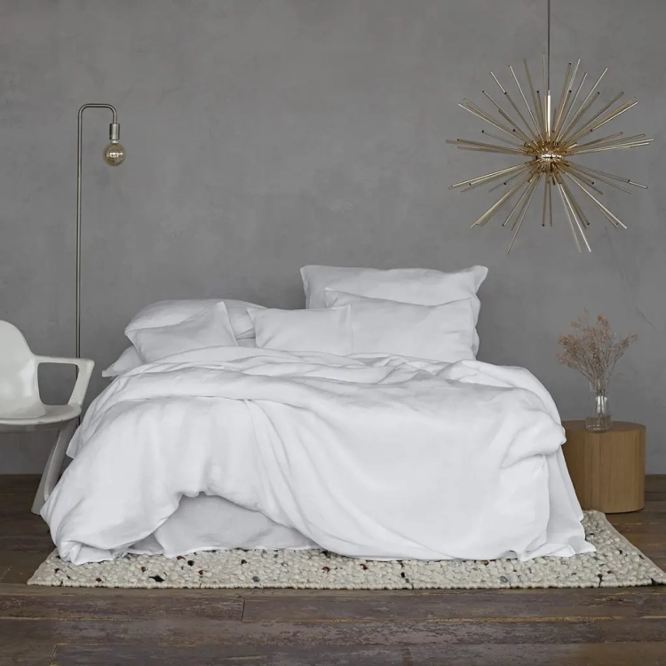 Podwójne łóżko z białą lnianą pościelą w minimalistycznej sypialni