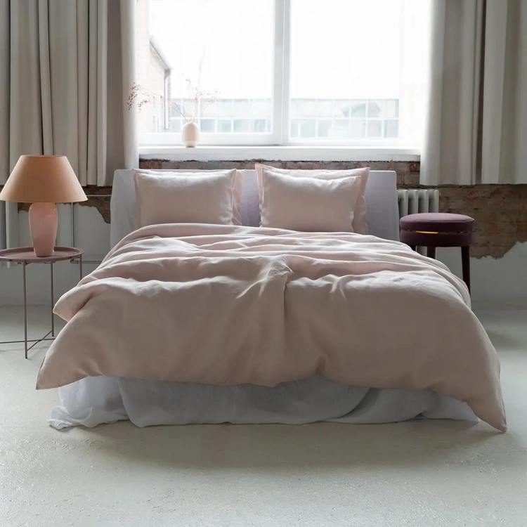 Łóżko z lnianą pościelą w kolorze pudrowego różu w sypialni.