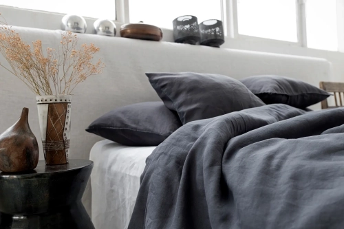 Naturalna pościel z lnu w odcieniu głębokiej szarości, w surowym, nowoczesnym wnętrzu