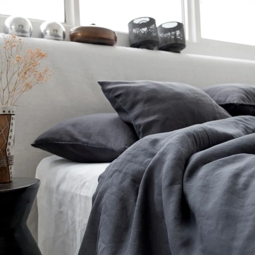 Naturalna pościel z lnu w odcieniu głębokiej szarości, w surowym, nowoczesnym wnętrzu