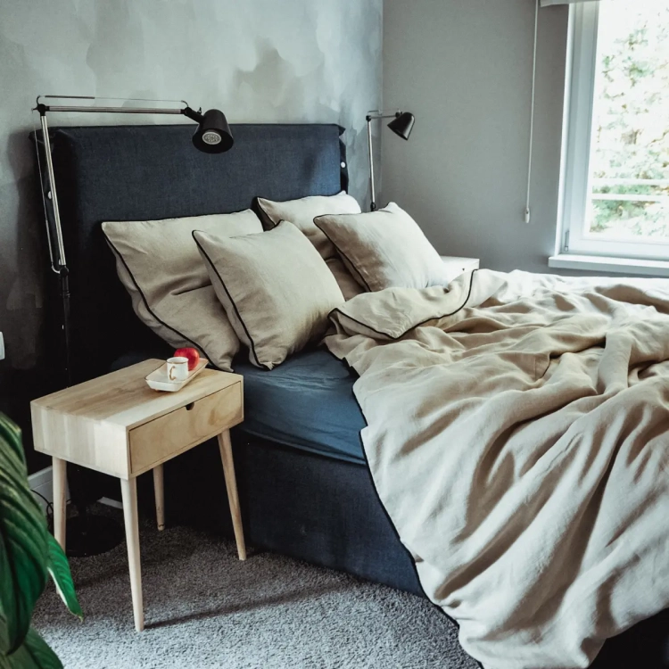 lniany komplet pościeli naturalnej z czarną wypustką na granatowym tapicerowanym łóżku